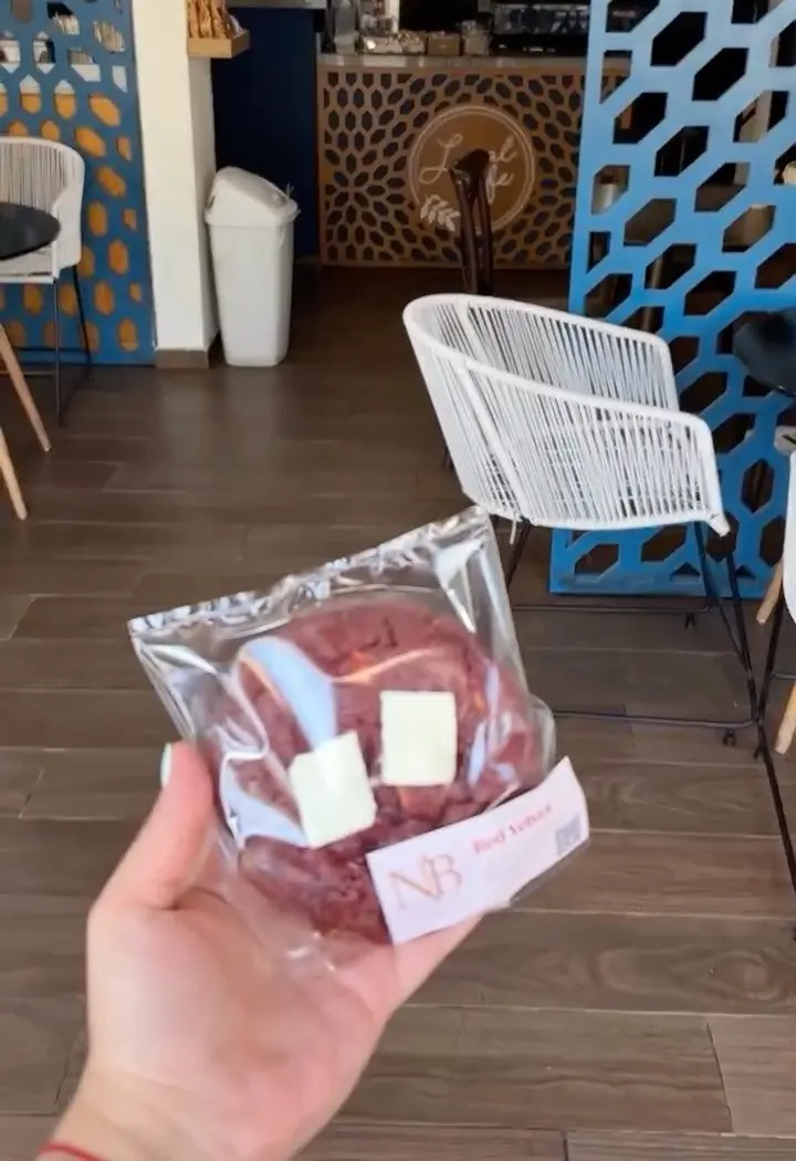 Una galleta en su bolsita frente a la barra y la celosía azul de Local Café